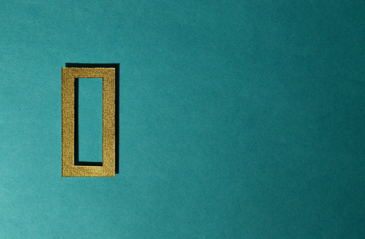 A gold rectangular frame casting a shadow on a teal background, minimal and artistic.
