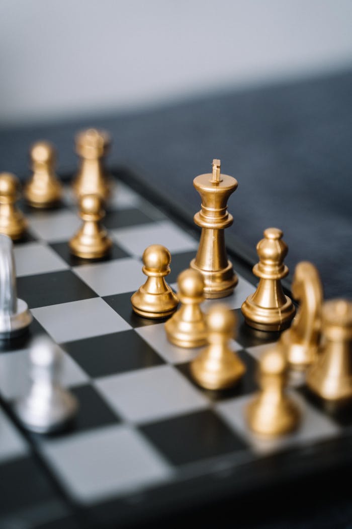 Close-up of golden chess pieces on a chessboard, ready for a strategic move.